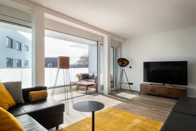 Ferienwohnung Industrial Style - Offener Wohnbereich mit Zugang zum Balkon